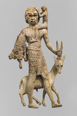 A rare ivory statuette carved in the round, showing a Nubian carrying a monkey, oryx and leopard skins and found in the residence of the rab ekalli at Fort Shalmaneser