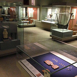 Museum gallery with glass display cases containing a variety of small artefacts from Mesopotamia