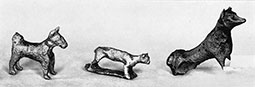 Three bronze figurines of standing dogs, though the central example looks very cat-like